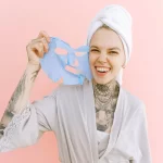 happy woman removing face mask after taking bath