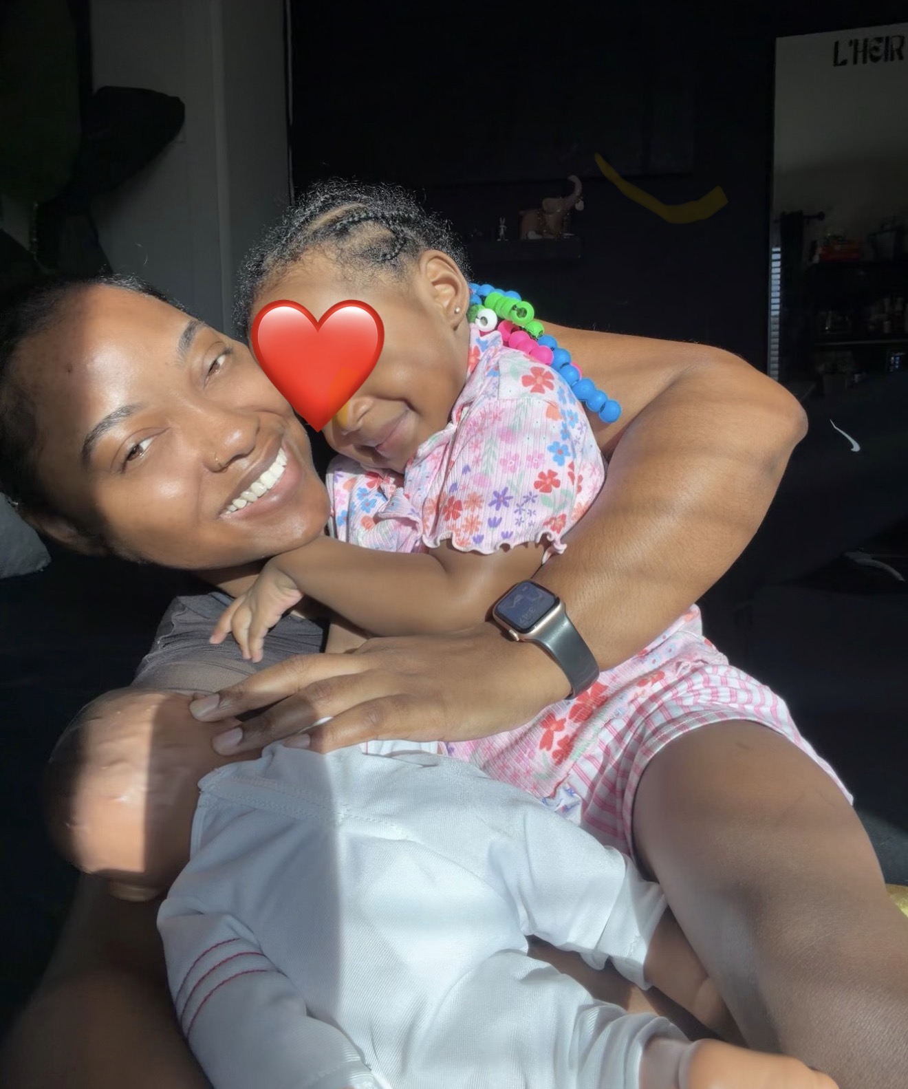 Morgan Ashley holding her daughter at home with the L'HEIR brand sign visible in the background  - Raising children by Birth Chart 