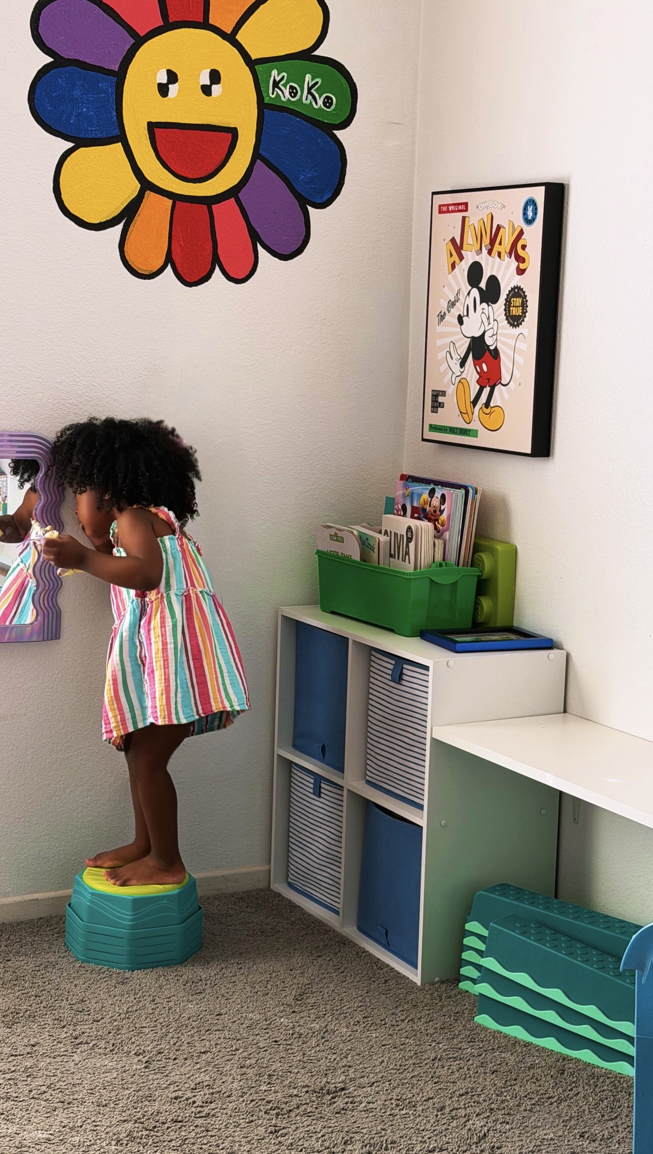 Toddler standing in her bedroom corner with a colorful Koko mural, bookshelf, and personalized storage - Raising children by Birth Chart 