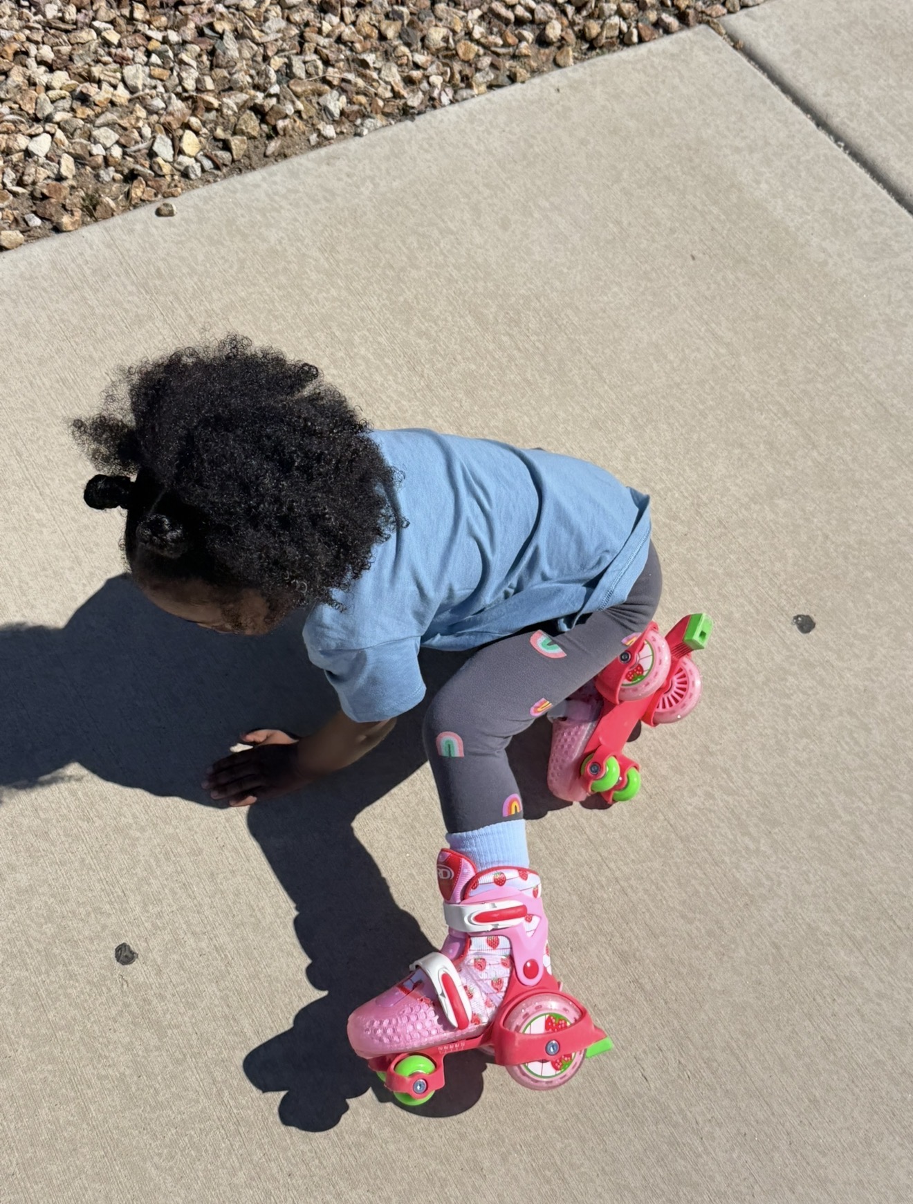 Toddler in strawberry roller skates learning to skate on a sidewalk - Raising children by Birth Chart 